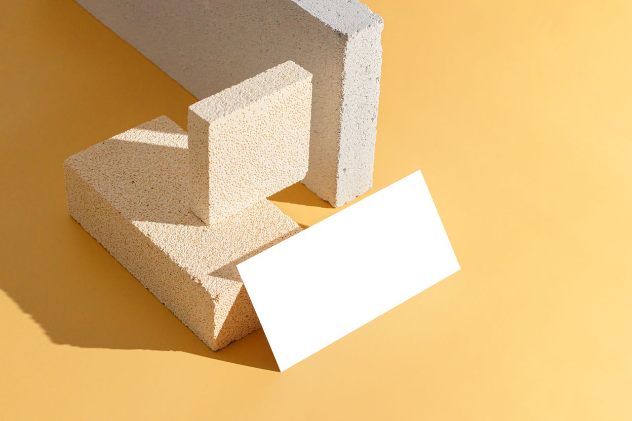 Geometric arrangement of concrete blocks on a yellow backdrop with ample copy space for design.