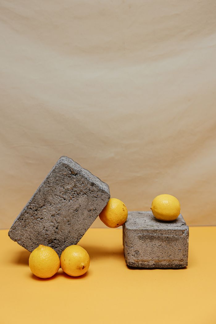 Artistic still life featuring lemons and concrete blocks in a minimalist setup.